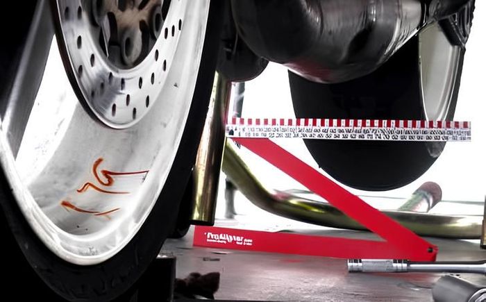 A motorcycle wheel is being measured with a red ruler