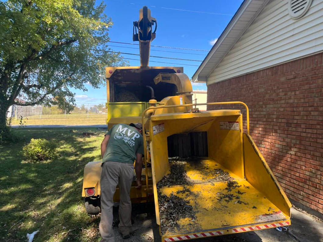 a man is working on a tree chipper in front of a house .