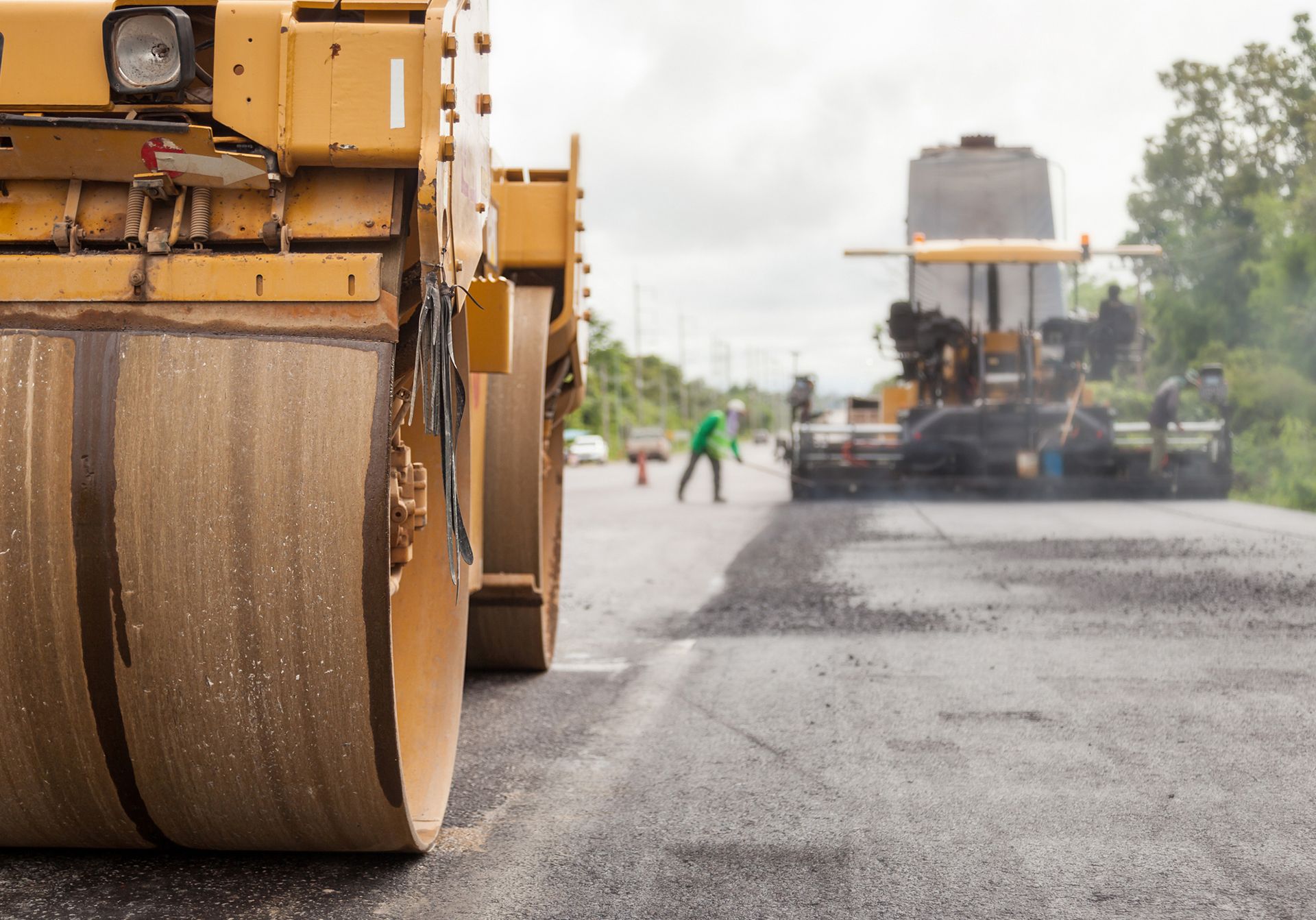 Road roller compacting fresh asphalt on a highway during road construction.