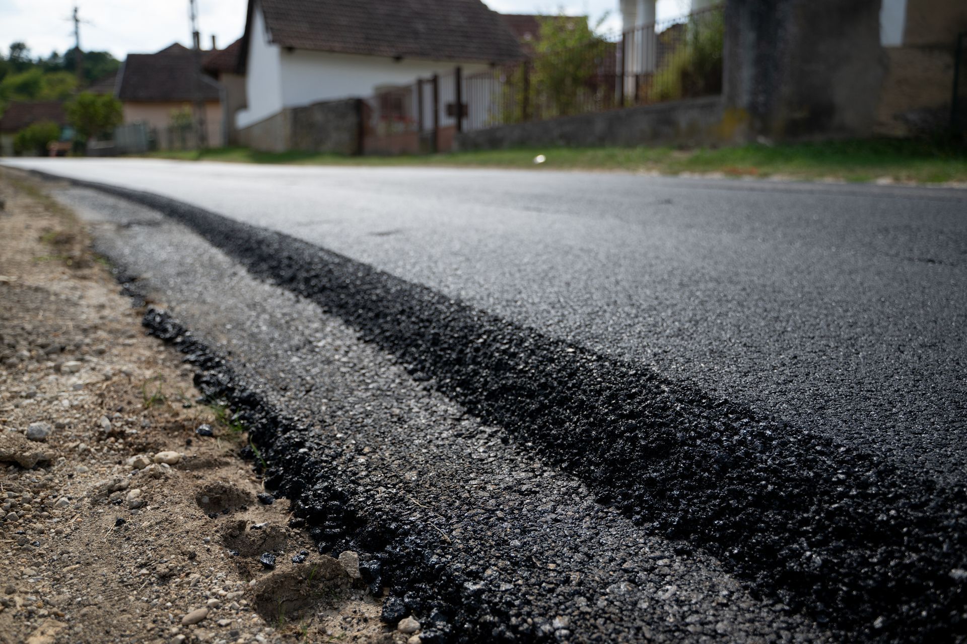 Freshly paved asphalt road in a rural setting, with low angle view of the black surface and roadside.