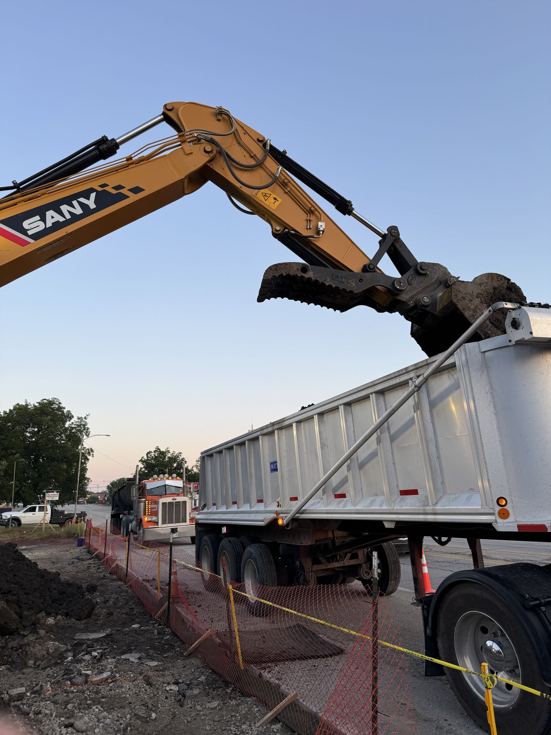 Yellow excavator on a pile of gravel, with a forest background.