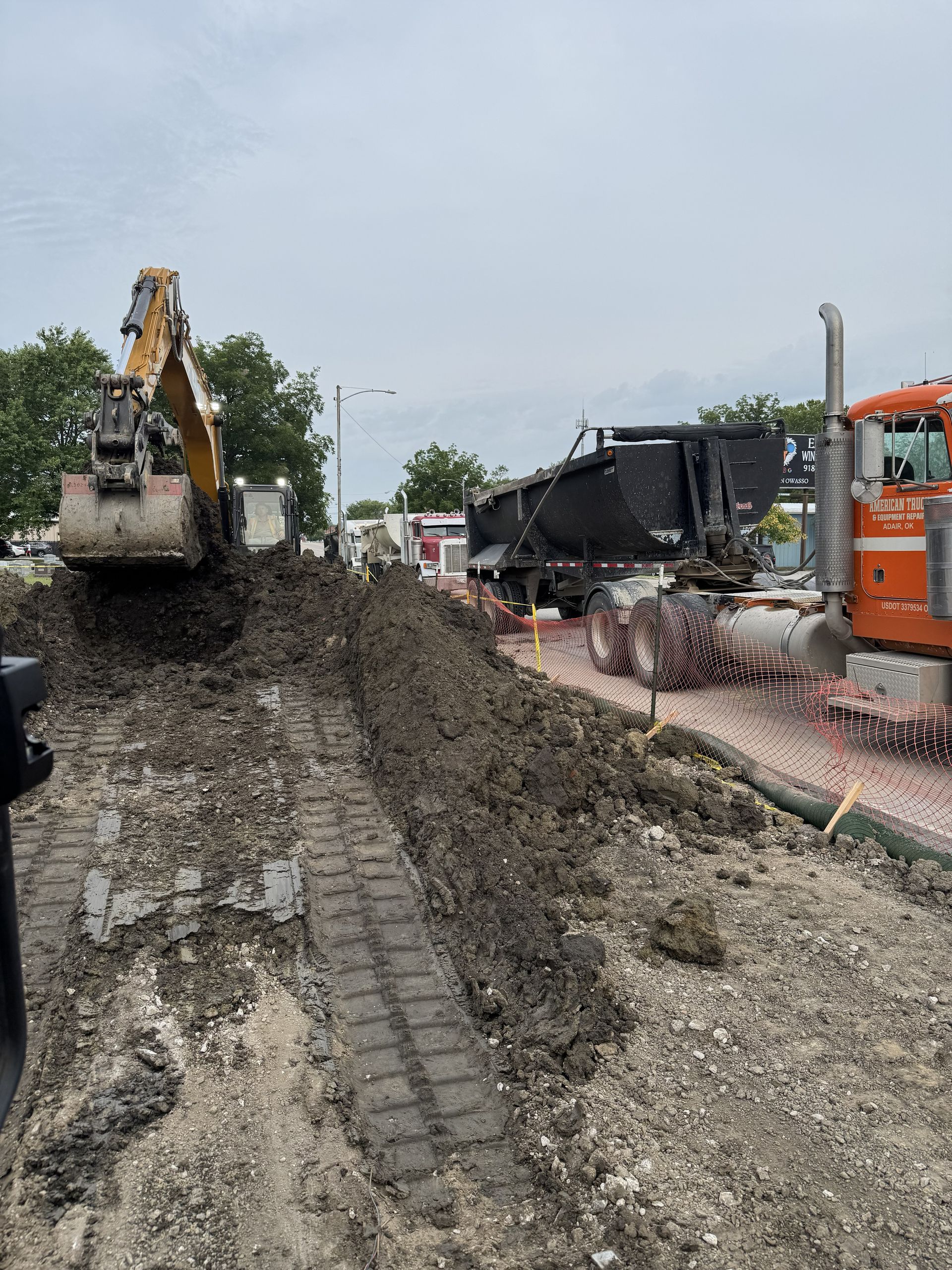 Yellow excavator digging dirt on a construction site under a blue sky.