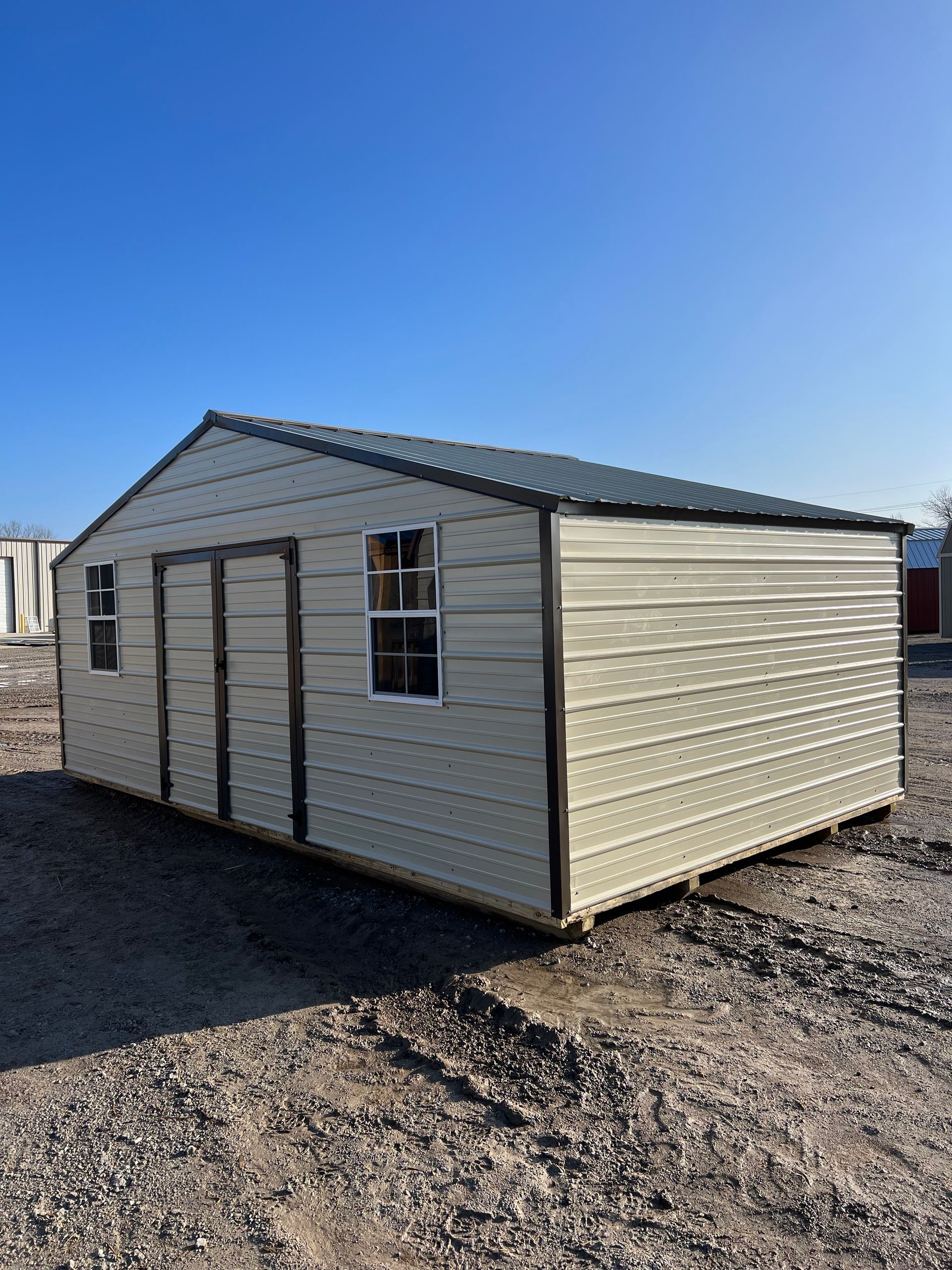 A metal shed is sitting in the middle of a dirt field.