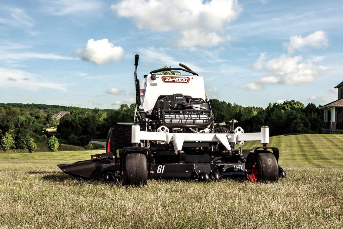 A lawn mower is sitting on top of a lush green field.