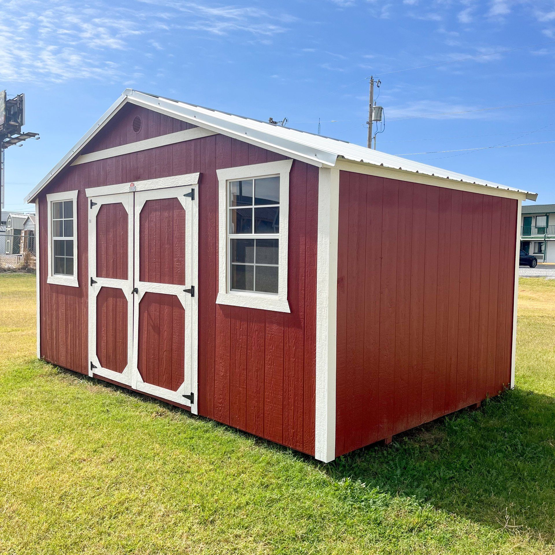 a red shed with white trim is sitting in the grass