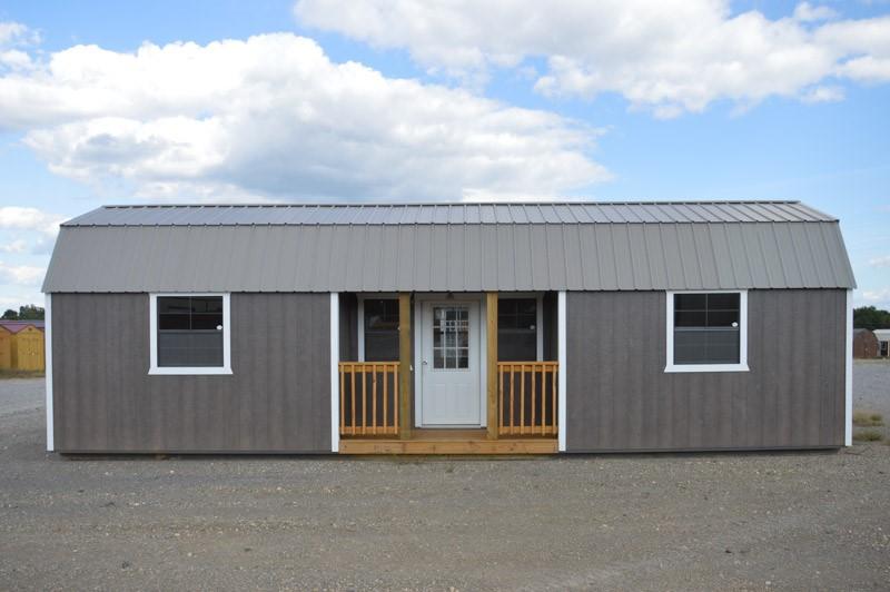 A gray shed with a porch and a white door