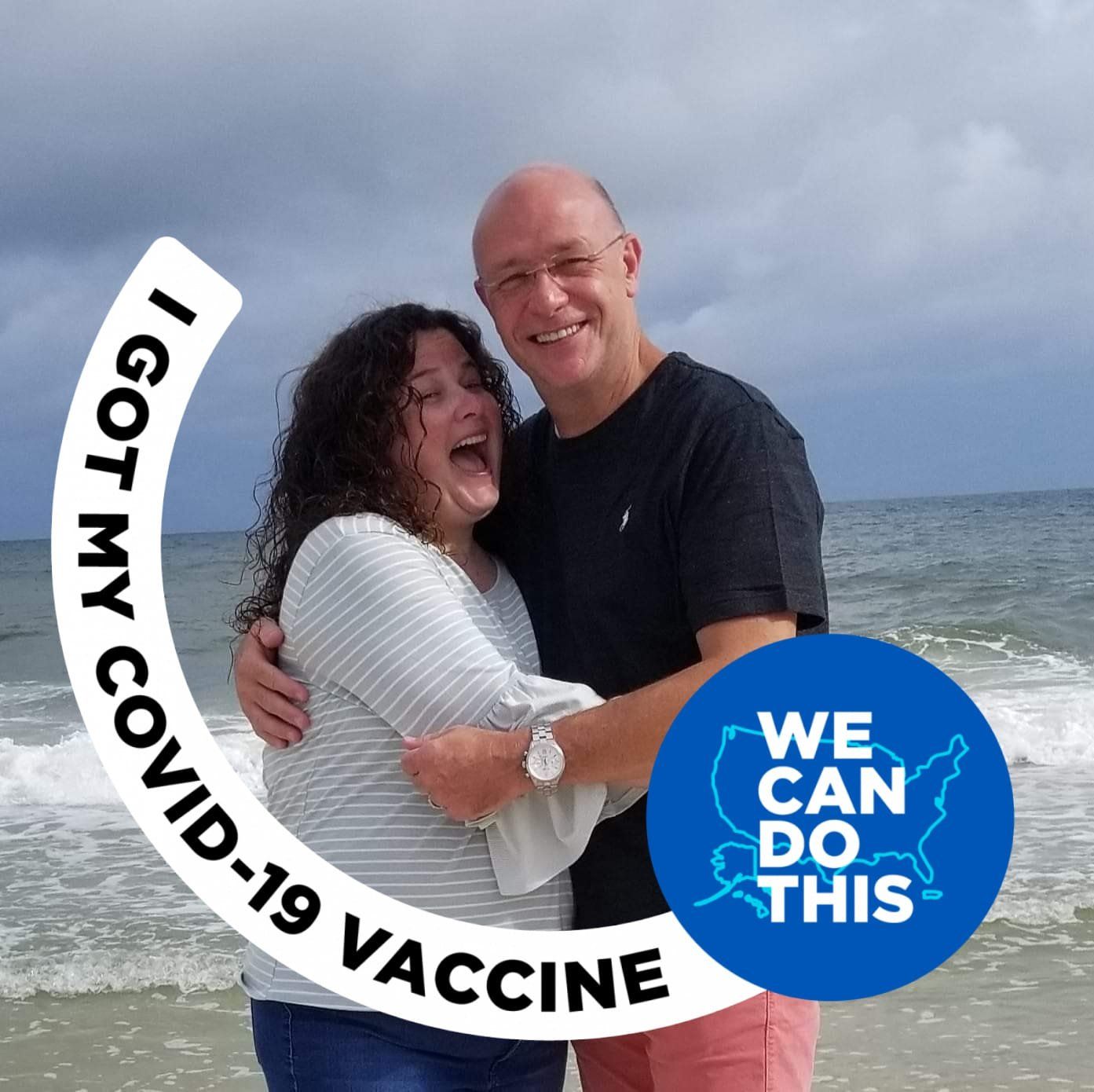 A man and woman hugging on the beach with a sticker that says i got my covid-19 vaccine