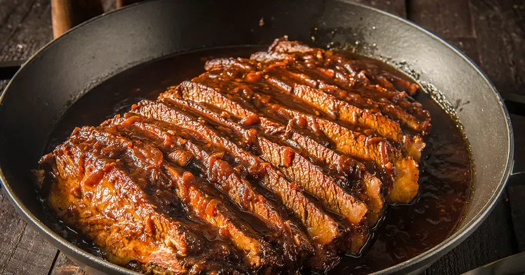 A large piece of meat is being cooked in a frying pan.