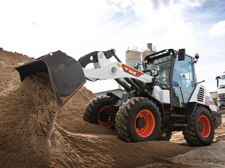 a bobcat tractor is loading a pile of dirt