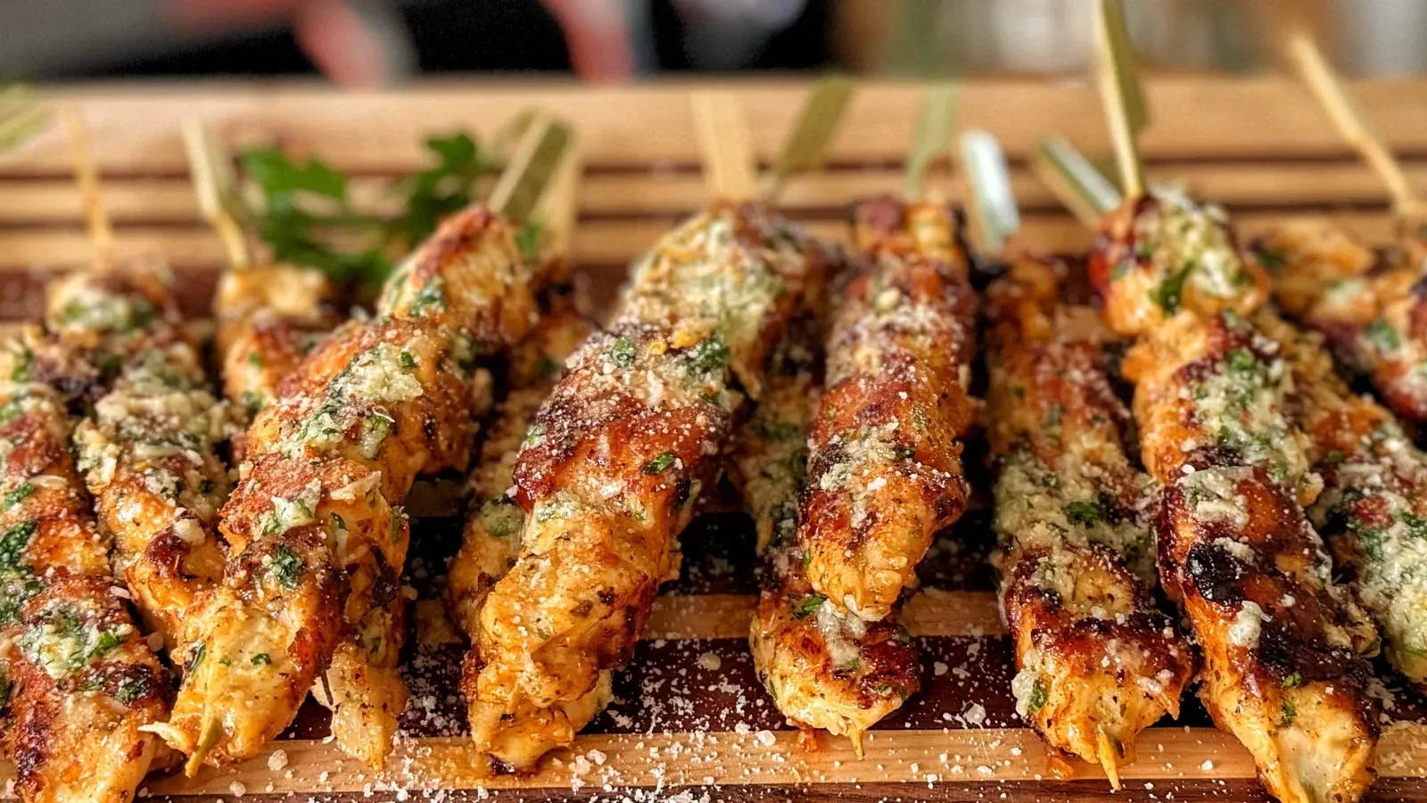 A wooden cutting board topped with chicken skewers on sticks.