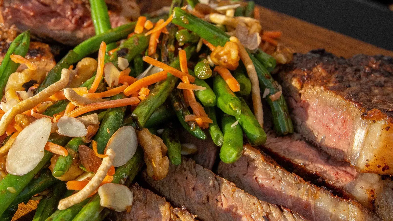 A close up of a plate of food with meat and vegetables on a table.