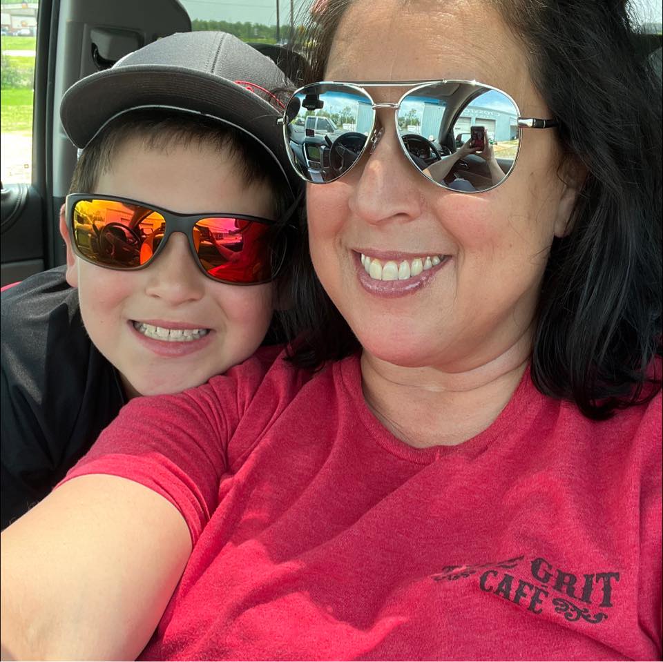 A woman and child wearing sunglasses and a red shirt that says grit cafe