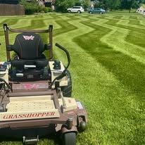 A grasshopper lawn mower is sitting on top of a lush green lawn.