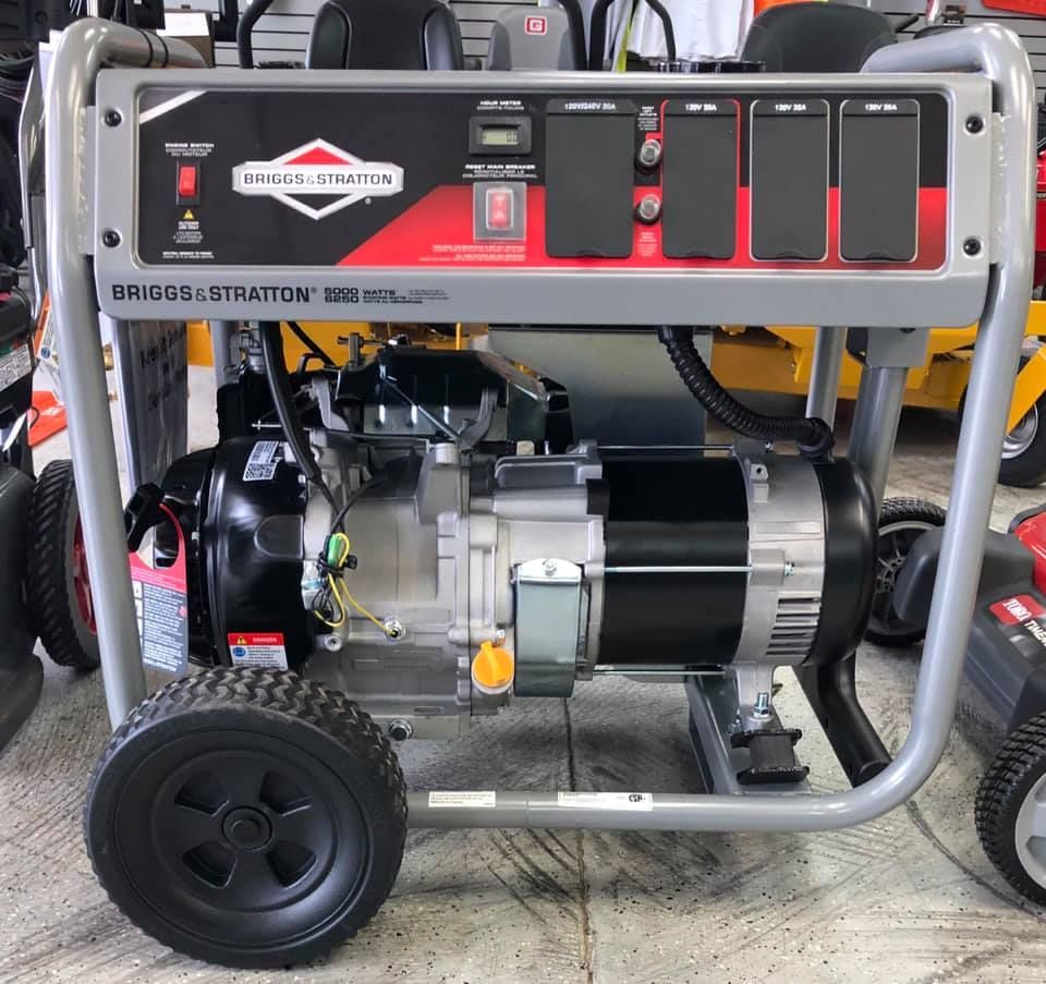 A briggs & stratton generator is sitting on the floor at M&D Enterprises & Lawnmower shops show booth