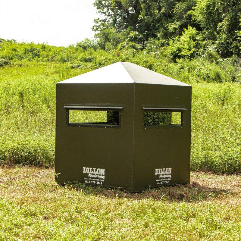 A hunting blind is sitting in the middle of a grassy field.