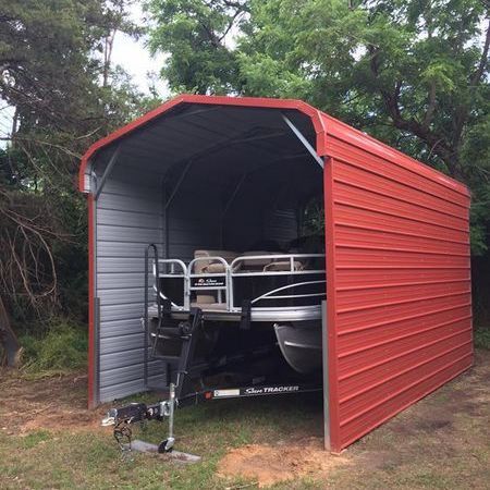 A boat is parked in a red metal shed.