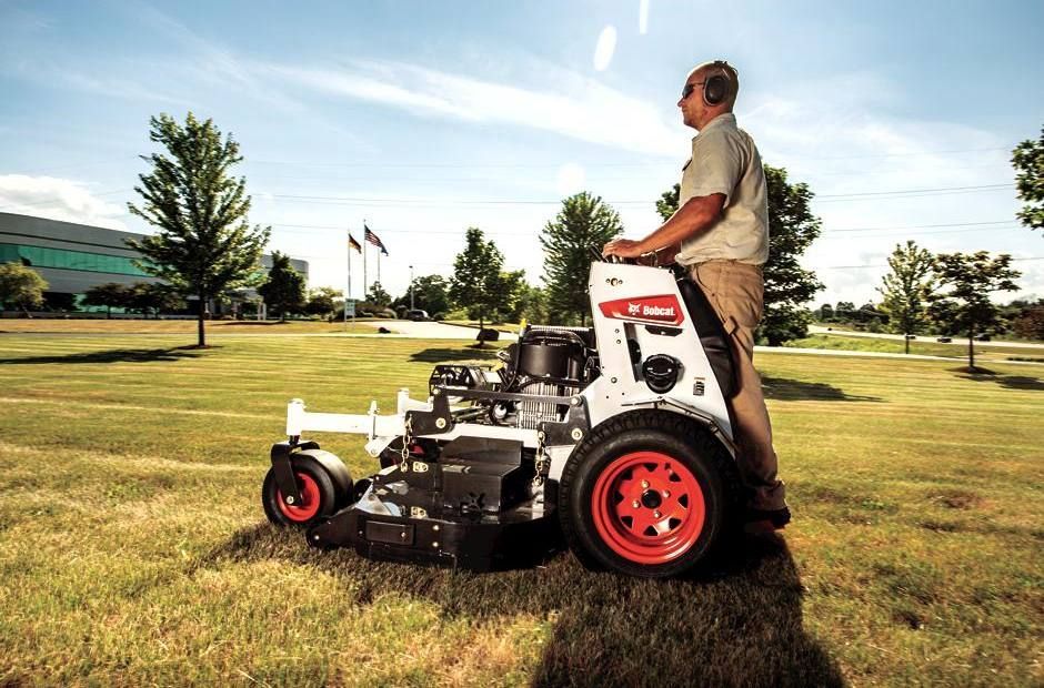 a man is driving a bobcat tractor in a park
