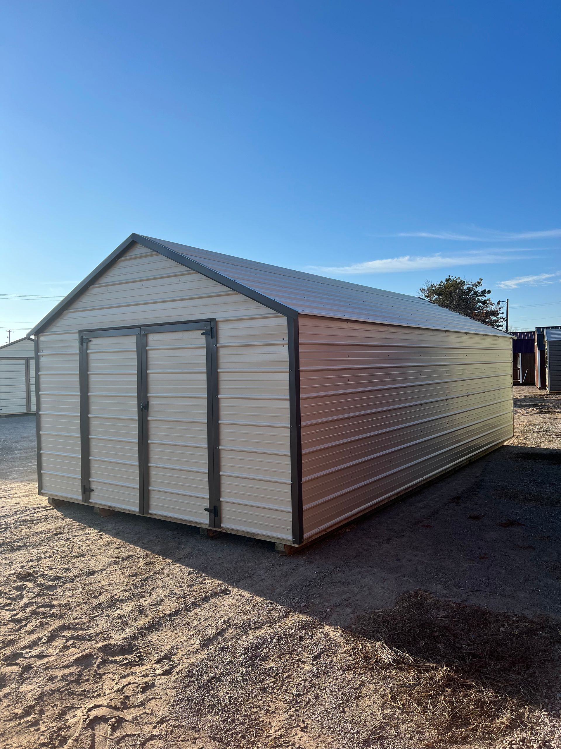 A metal shed is sitting in the middle of a dirt field.