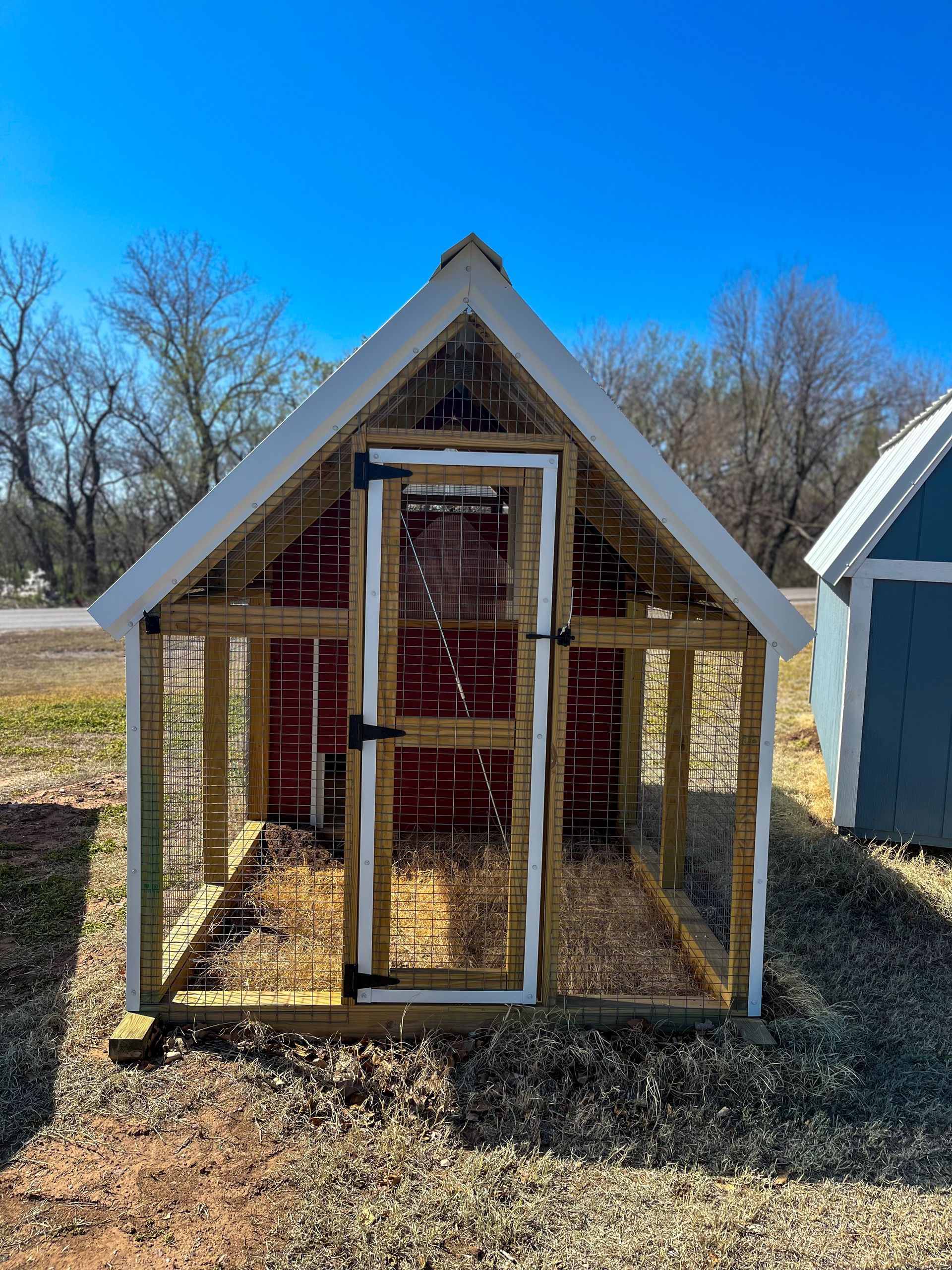 a small 6 x 10 chicken coop with a red roof and a white door