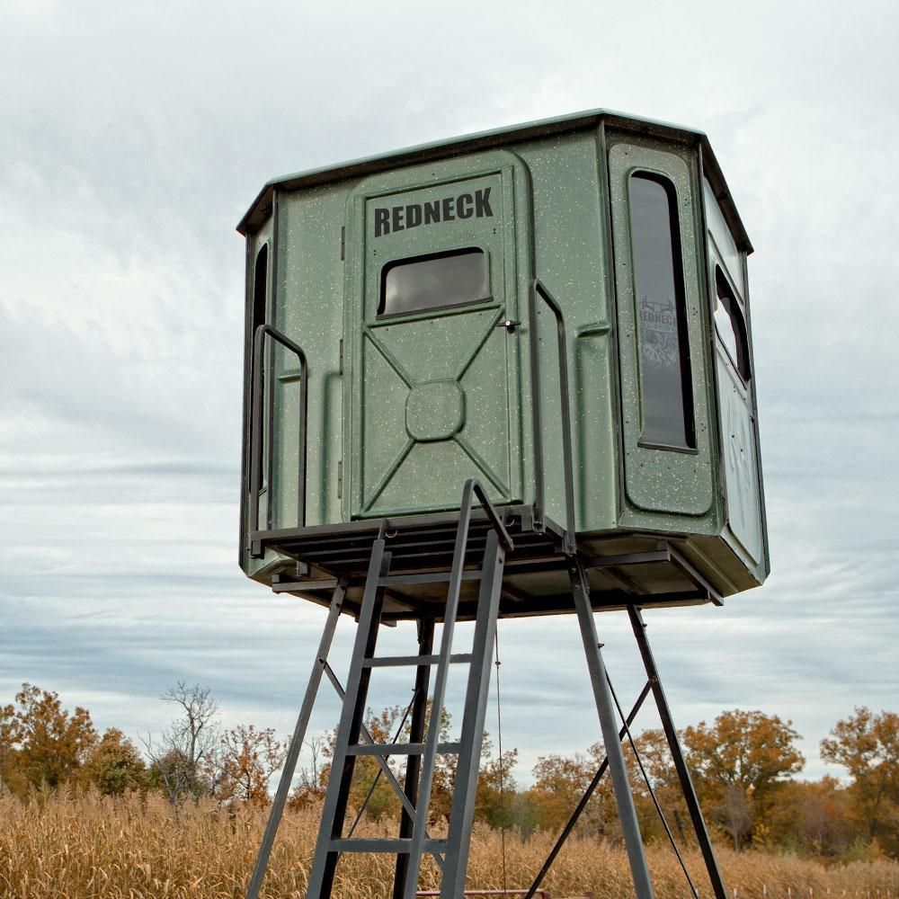 A redneck deer stand is sitting in the middle of a field.