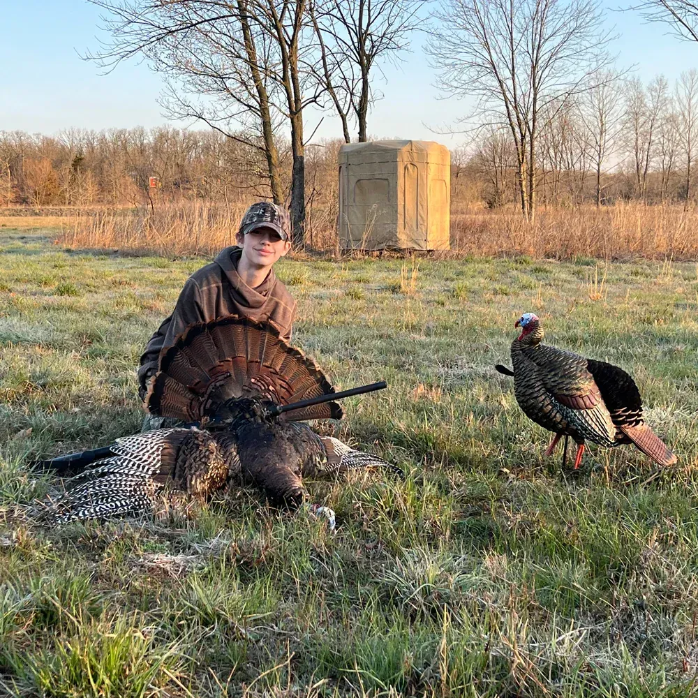 boy with turkey and blind in field 