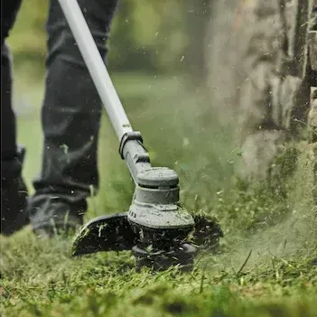 a person is using a string trimmer to cut the grass .