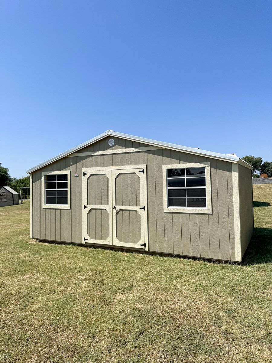 a small shed is sitting in the middle of a grassy field .