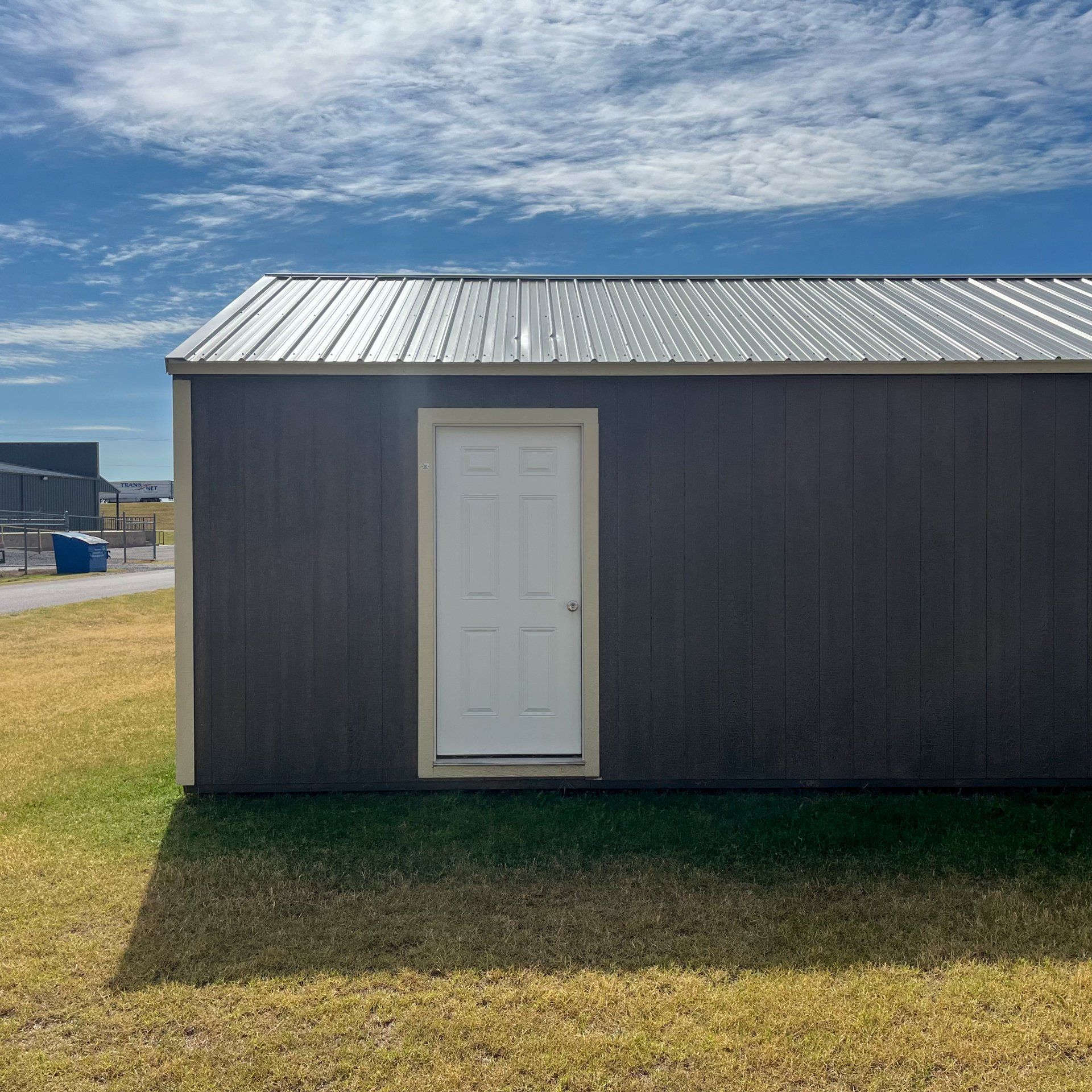 A small portable garage with a metal roof and a white door