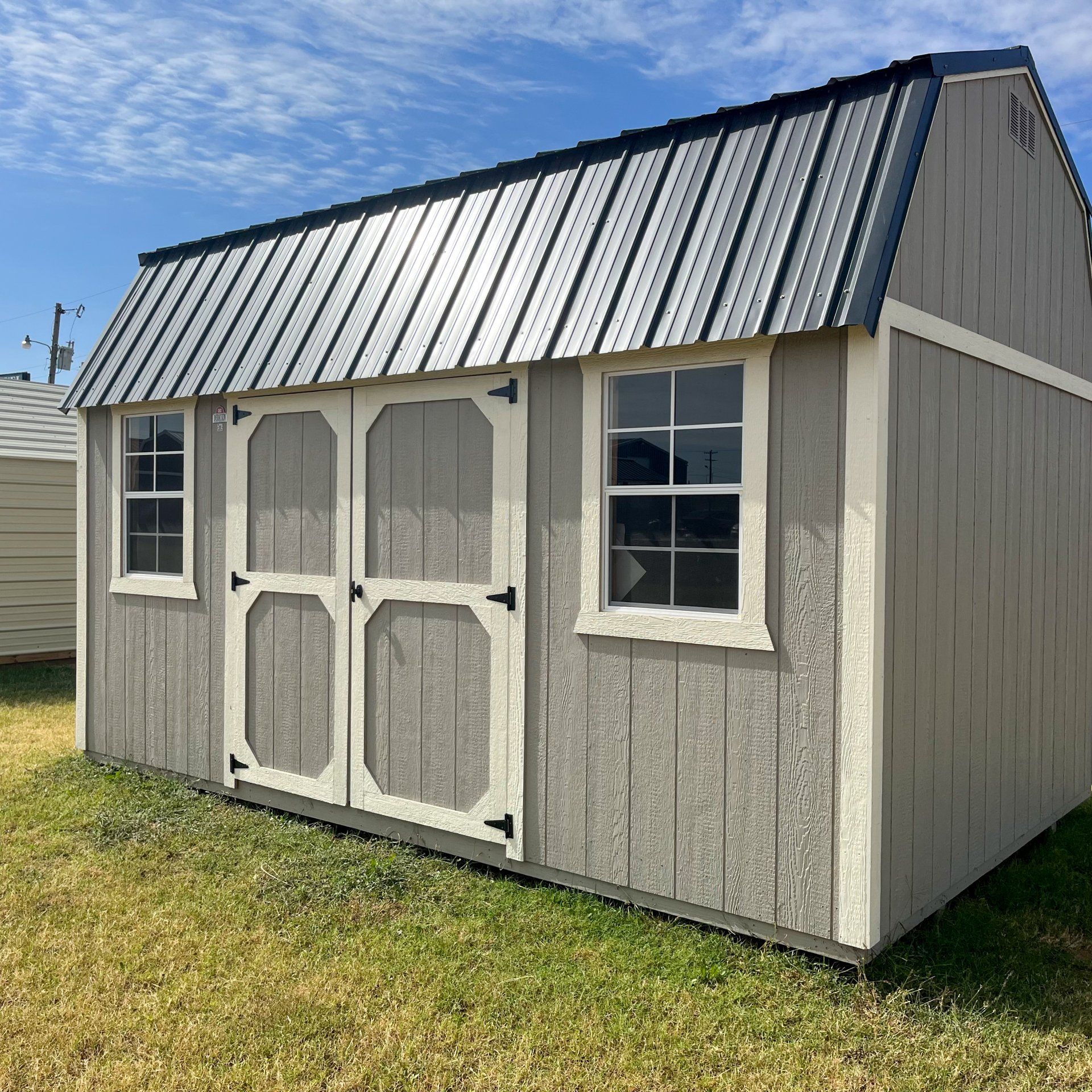 A gray and white side Lofted barn with a metal roof and windows