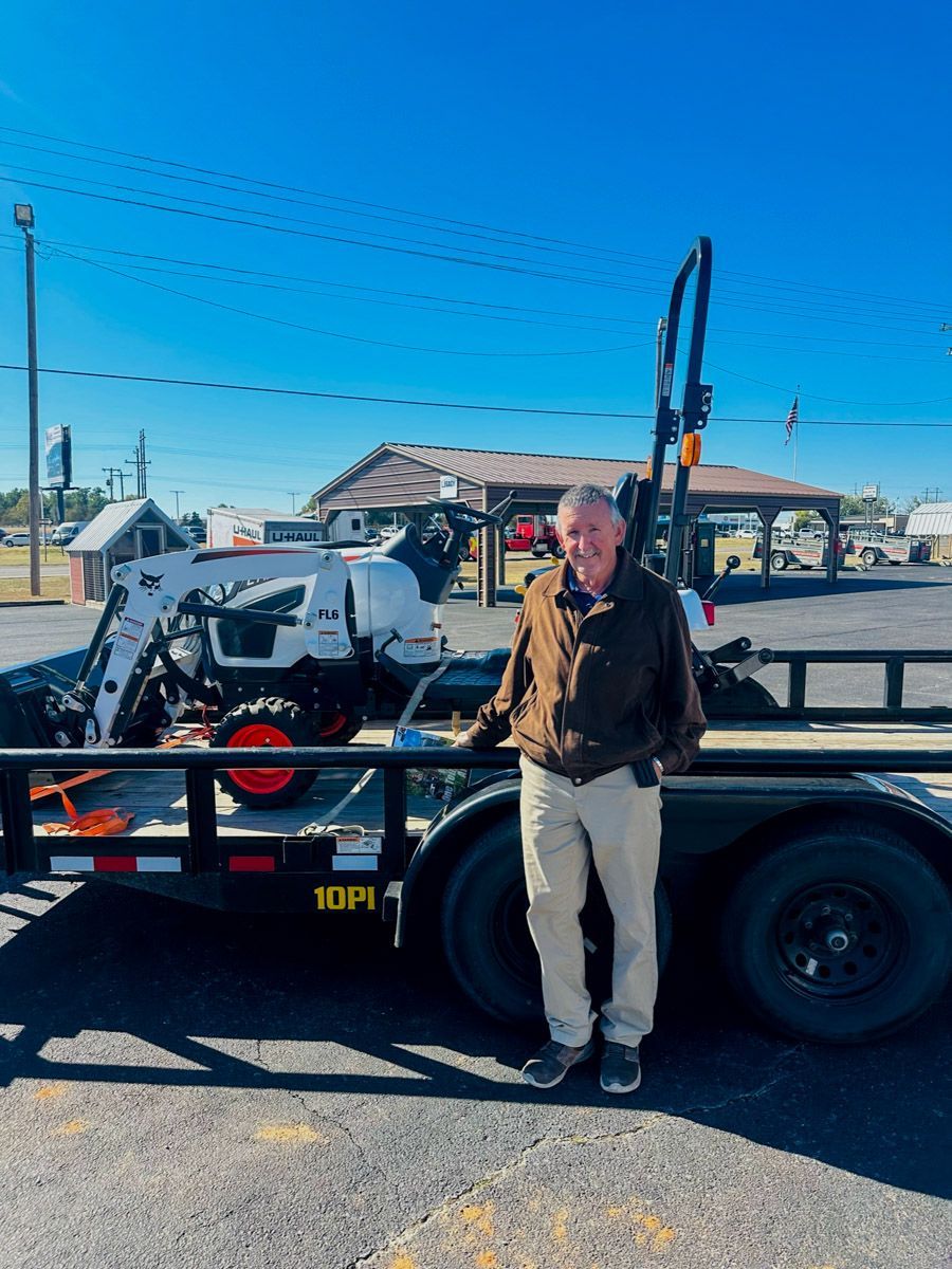 a man is driving a bobcat tractor carrying logs