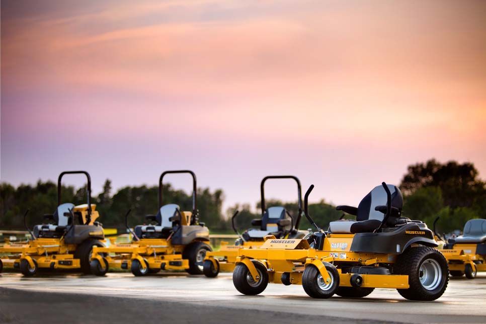 hustler lawn mowers are parked on the side of the road.