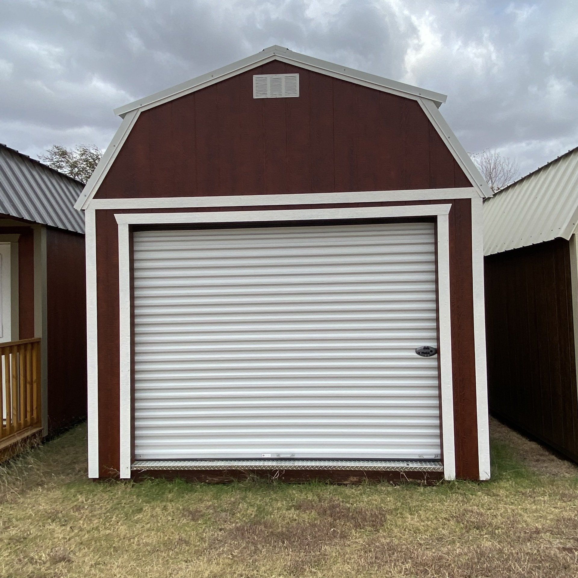 A brown side Lofted barn with a white garage door