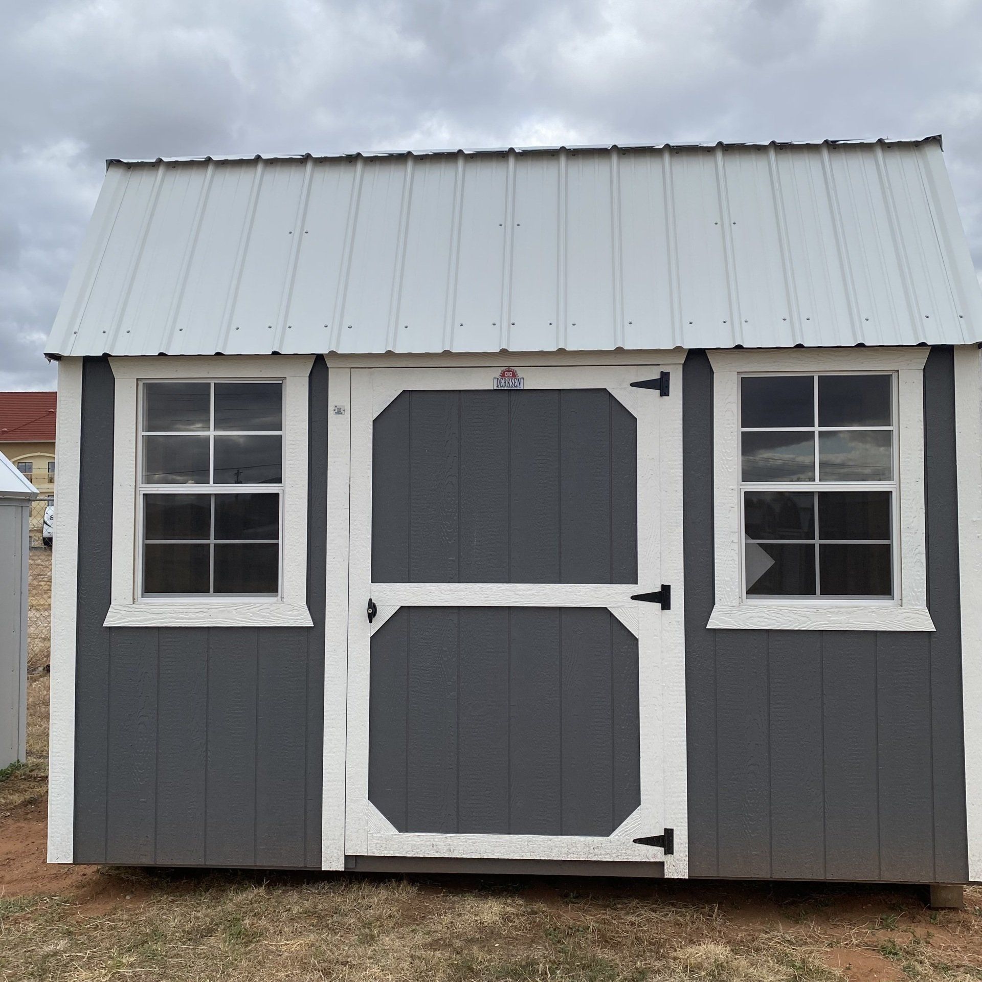 A gray and white shed with a white roof