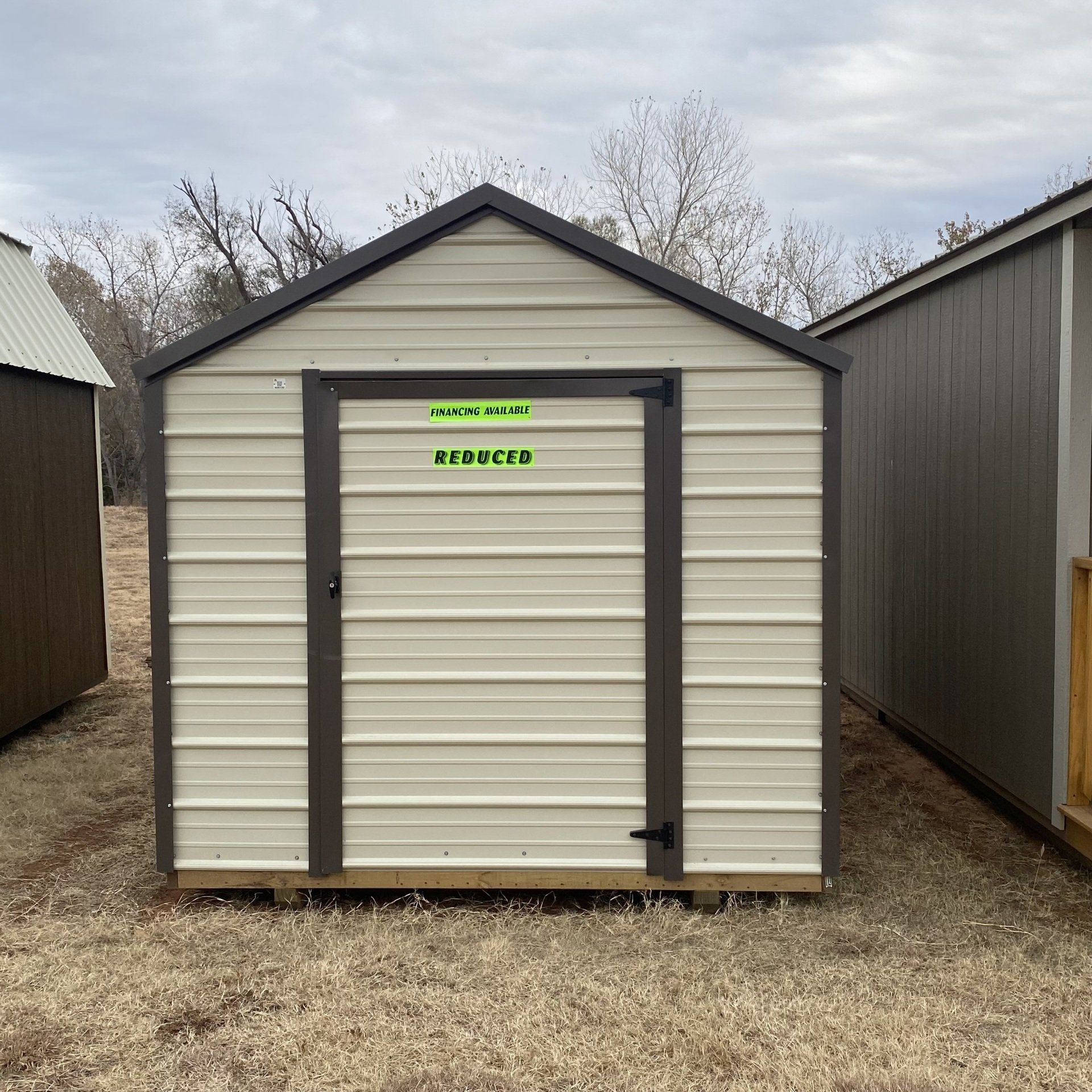 A white metal shed with a green sticker on the door