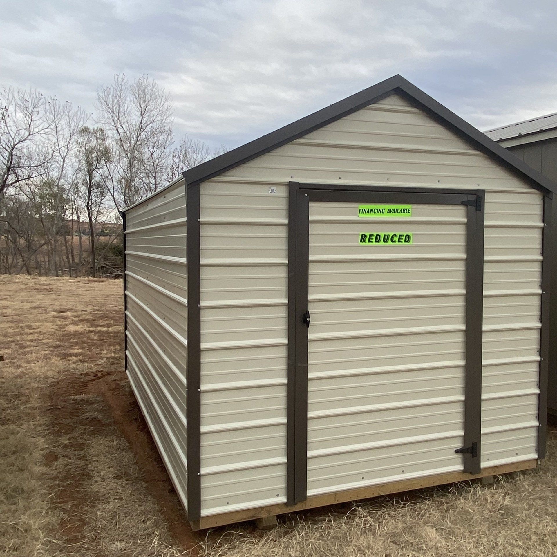 A metal shed with a green sign on the door that says approved
