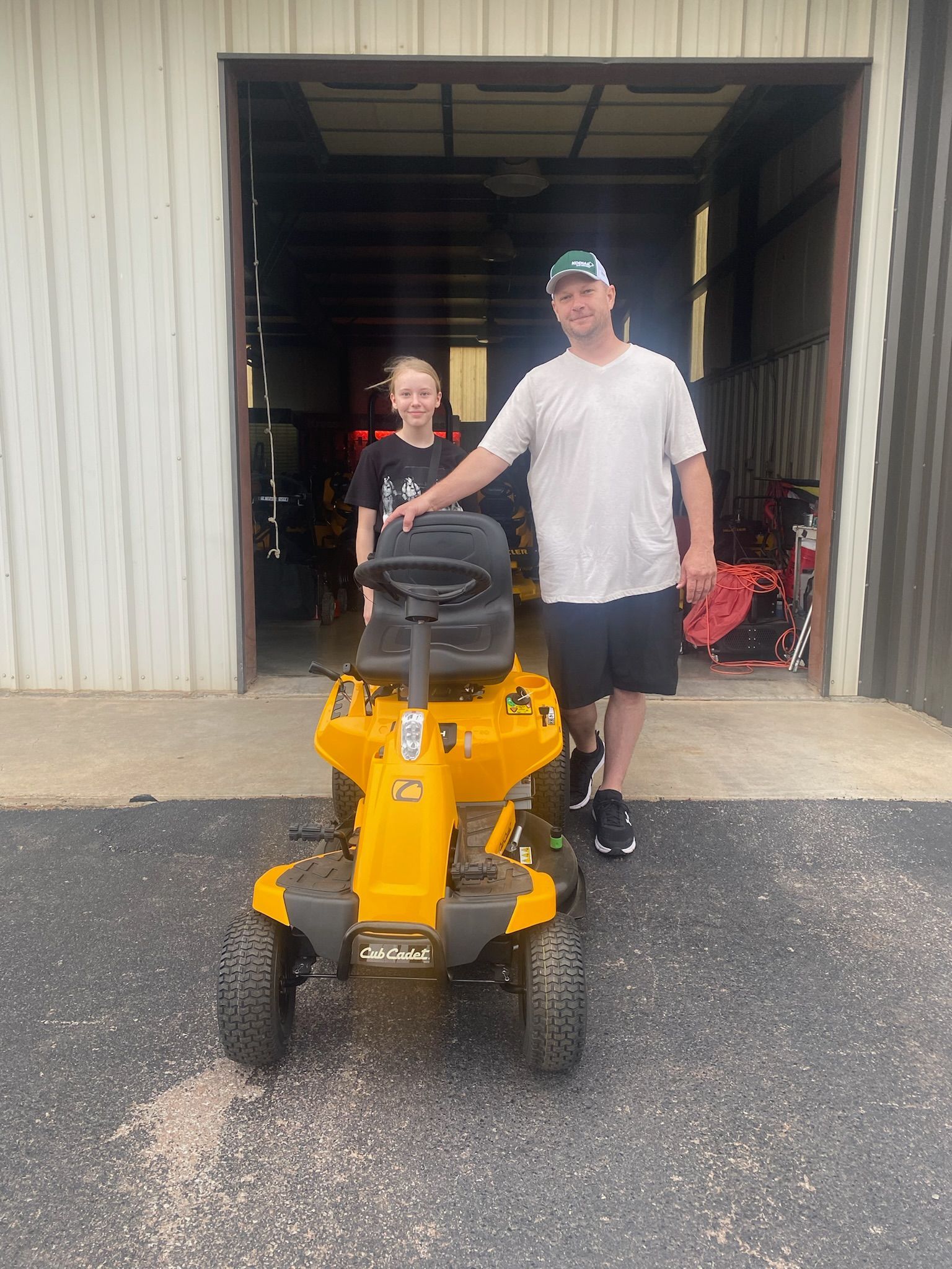 A man and a boy are standing next to a yellow lawn mower.