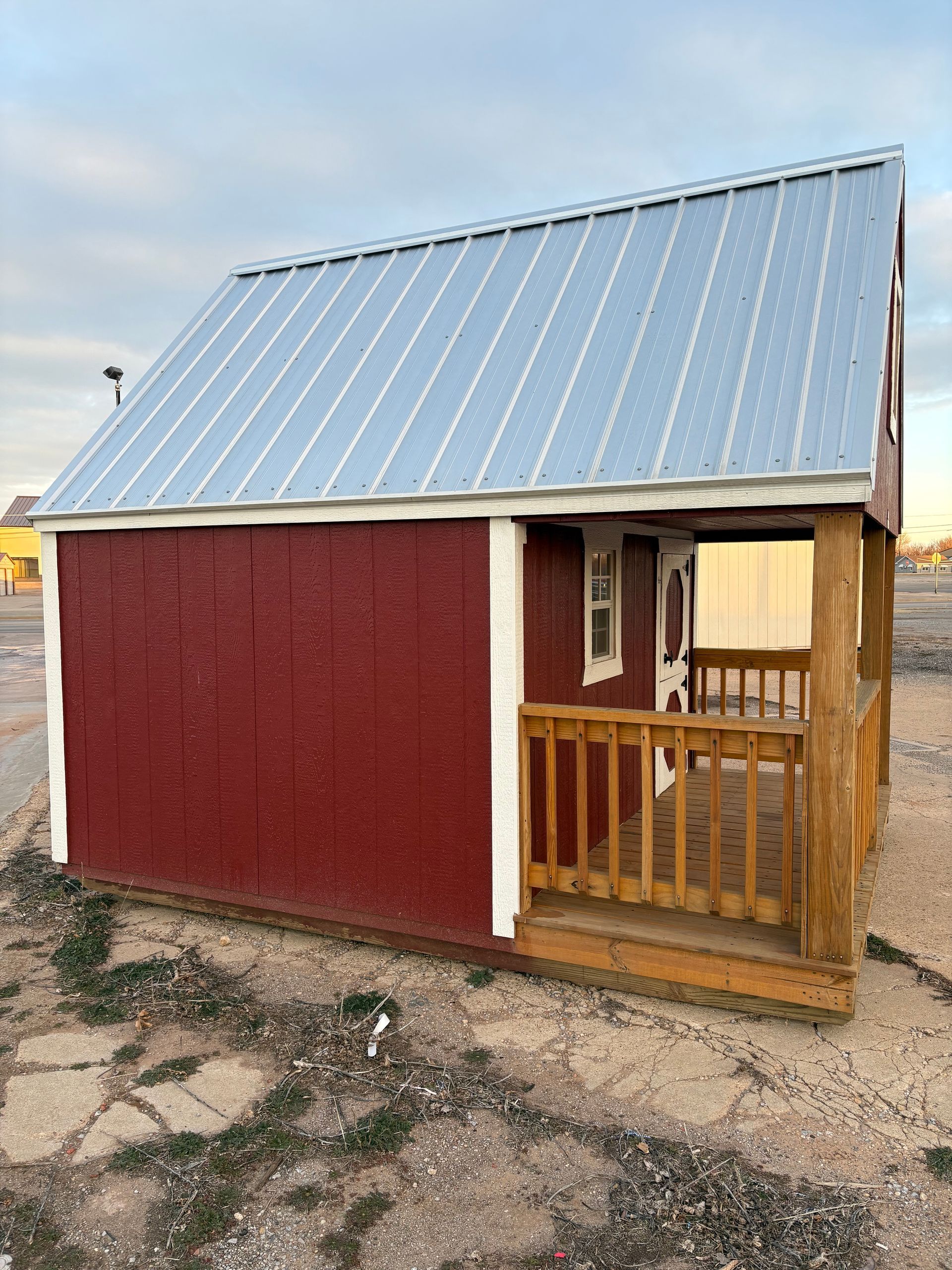 A small red shed with a metal roof and a porch.