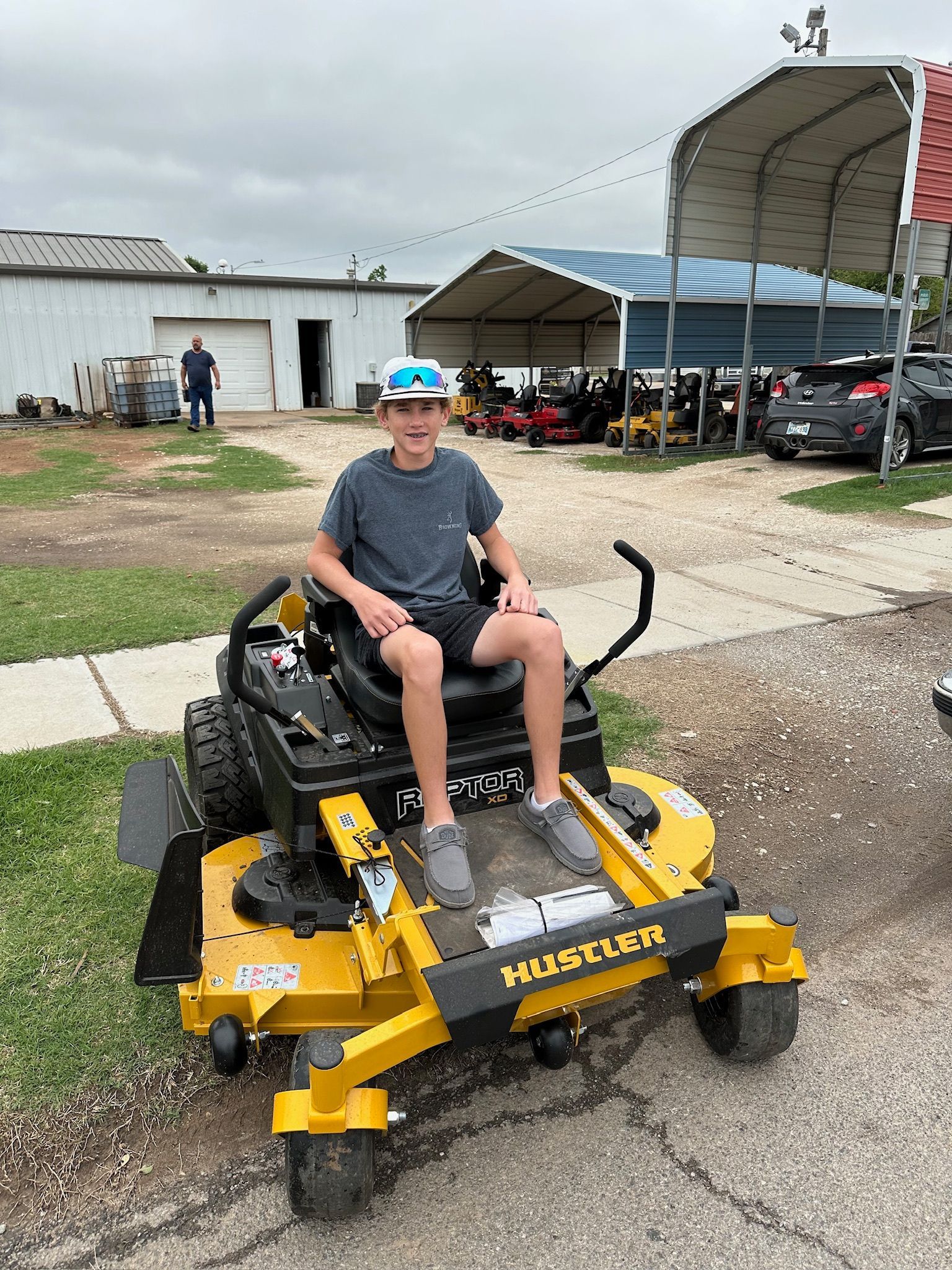A young boy is sitting on a yellow and black lawn mower.
