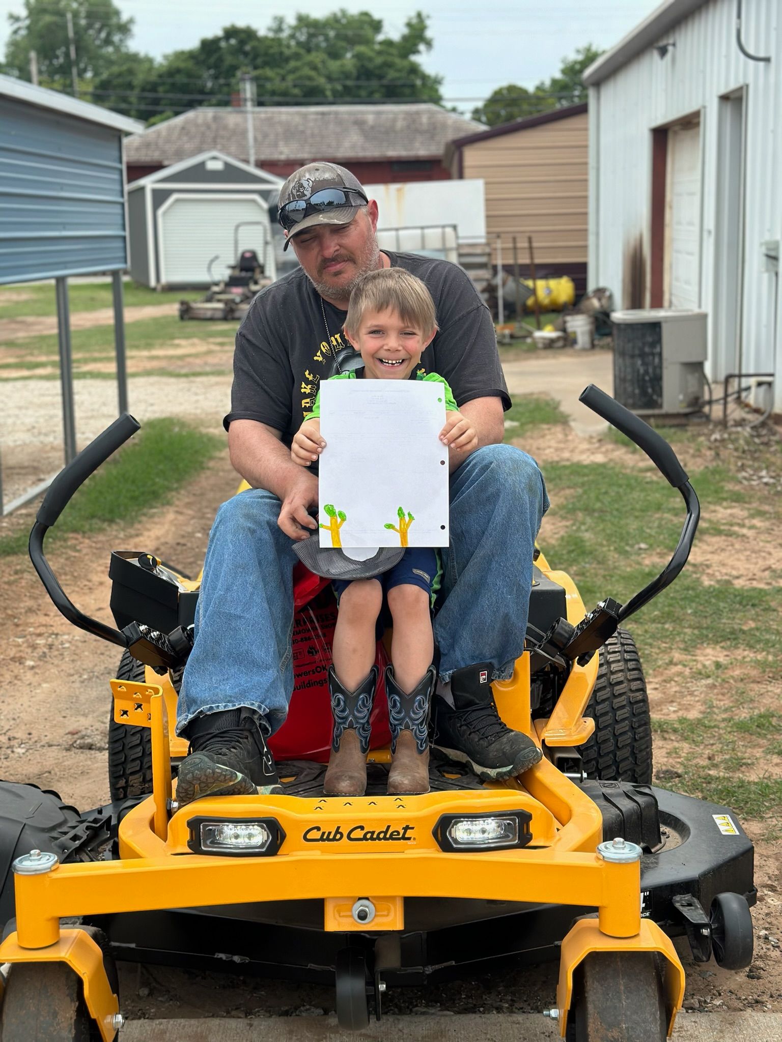 A man is sitting on a lawn mower holding a child.