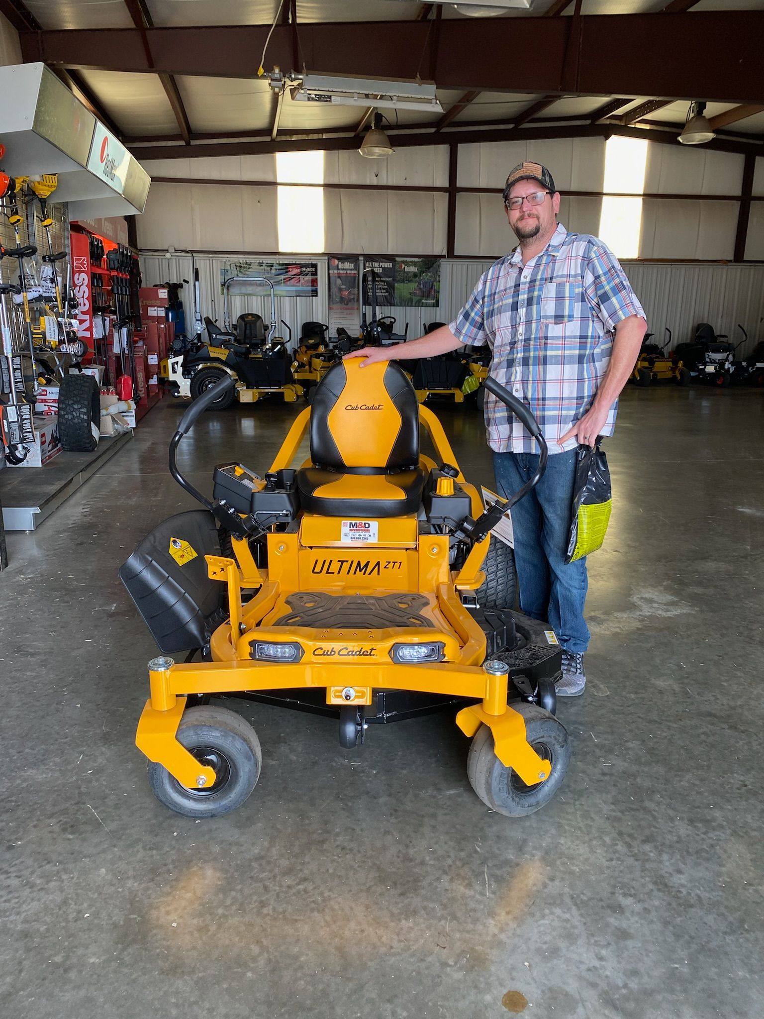 A man is standing next to a yellow lawn mower in a garage.