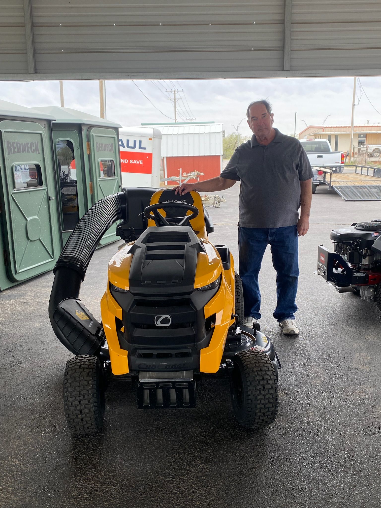 A man is standing next to a yellow lawn mower in a garage.