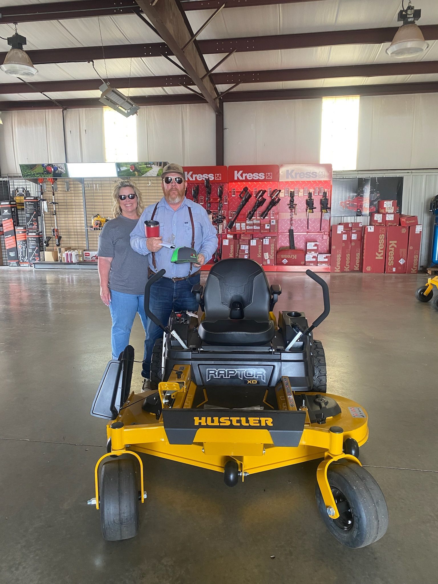 Two men are standing next to a yellow lawn mower in a store.