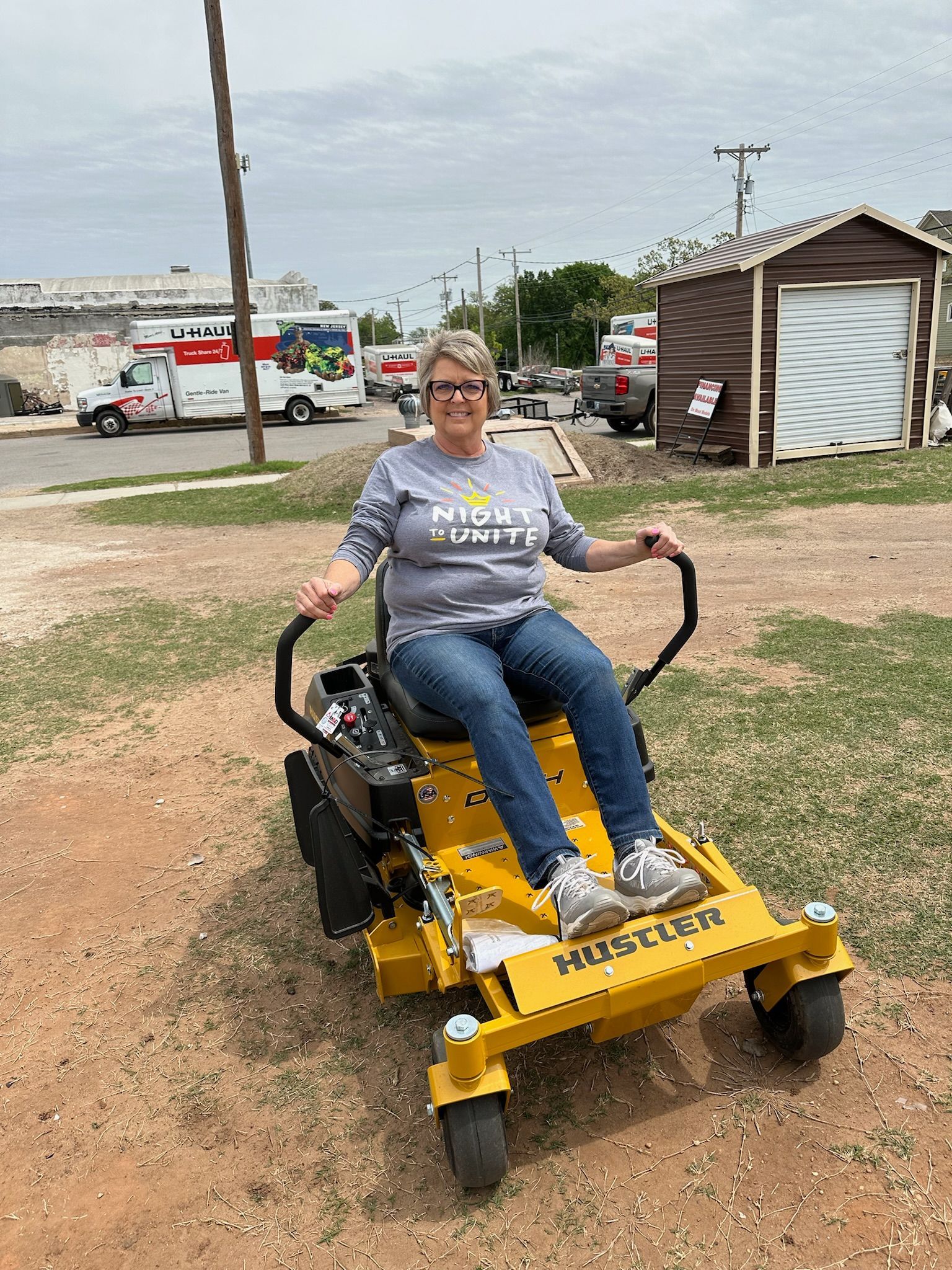 A woman is sitting on a yellow lawn mower.