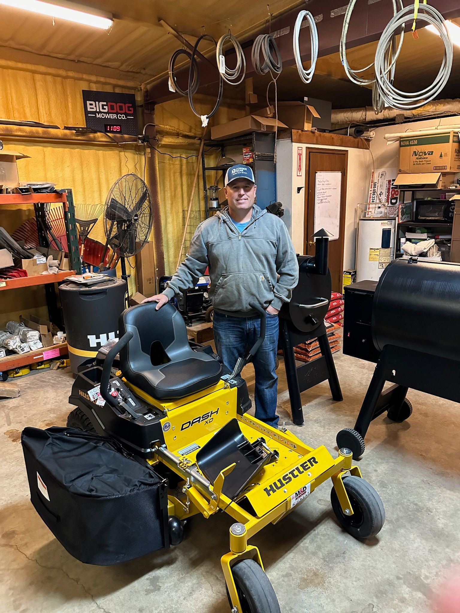 A man is standing next to a yellow lawn mower in a garage.