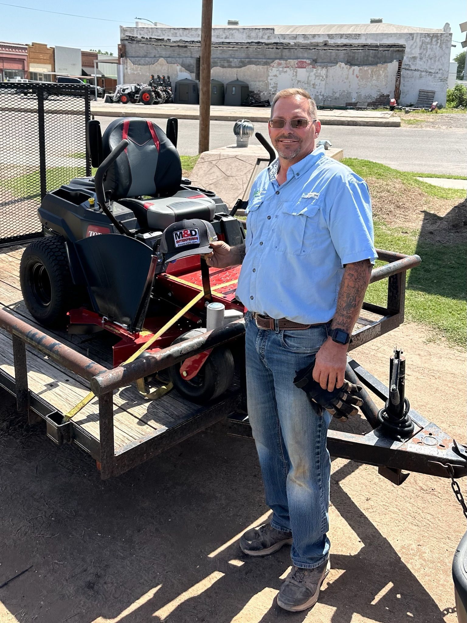 A man is standing next to a lawn mower on a trailer.