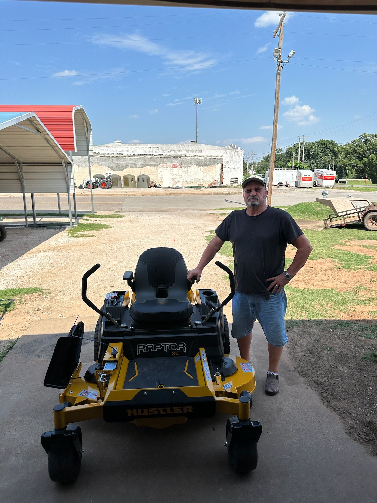 A man is standing next to a yellow and black lawn mower.