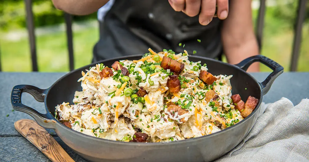 A person is cooking food in a pan on a table.