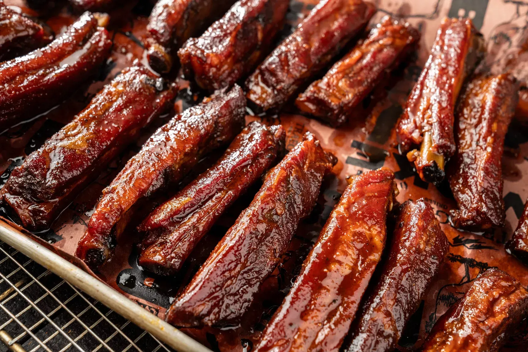 A pan filled with ribs covered in barbecue sauce.