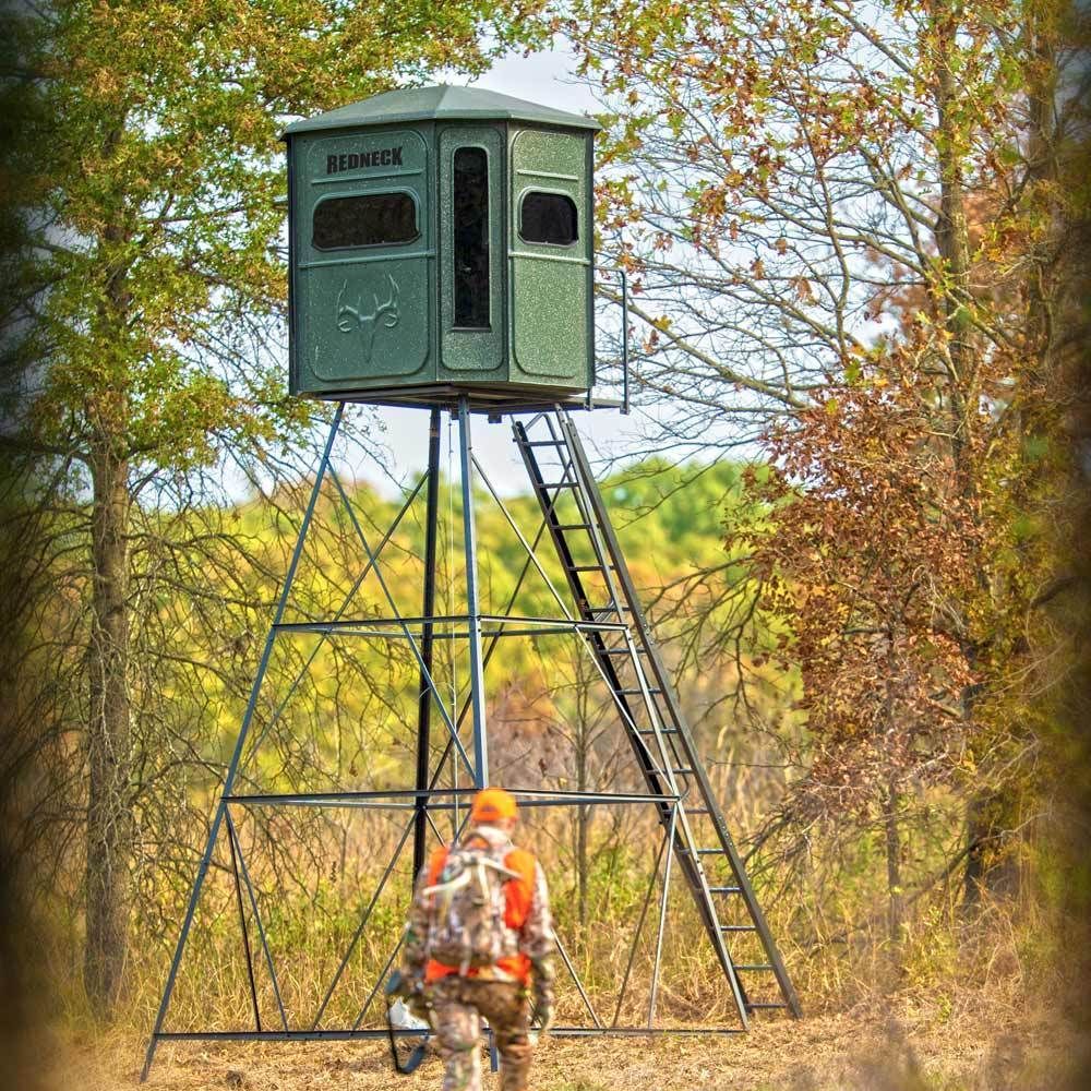 a hunter is walking towards a tower in the woods .