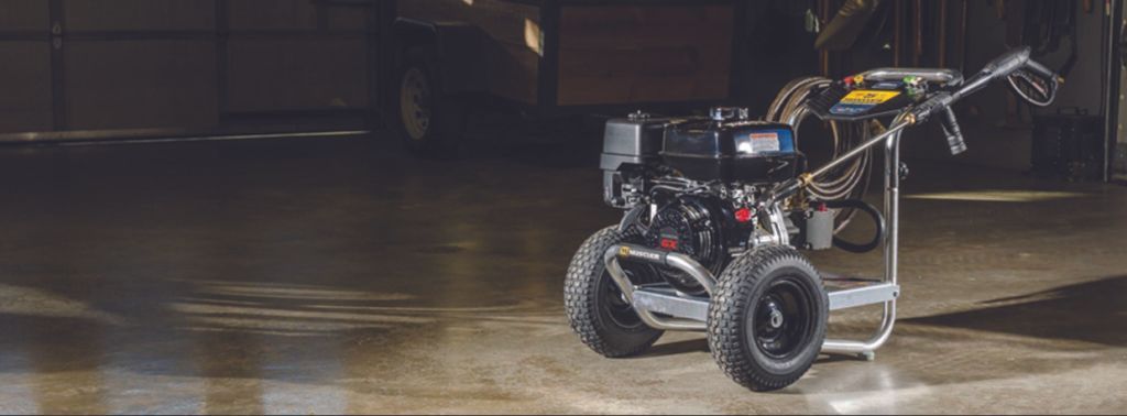 A gas powered pressure washer is sitting on a concrete floor in a garage.